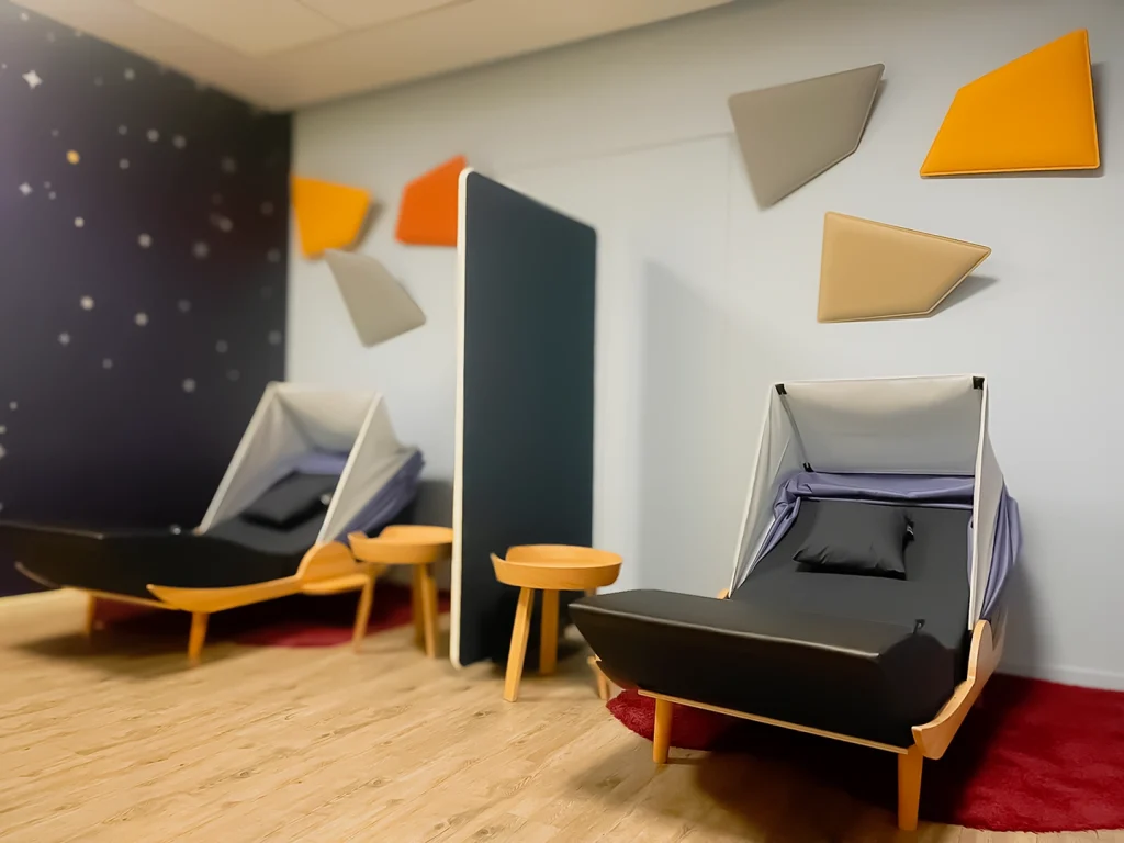 Fauteuils de repos dans un coin détente avec un mur à motifs géométriques et des tapis