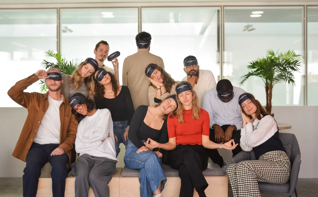 Équipe Nap&Up posant de manière détendue dans un bureau moderne avec des masques de sommeil