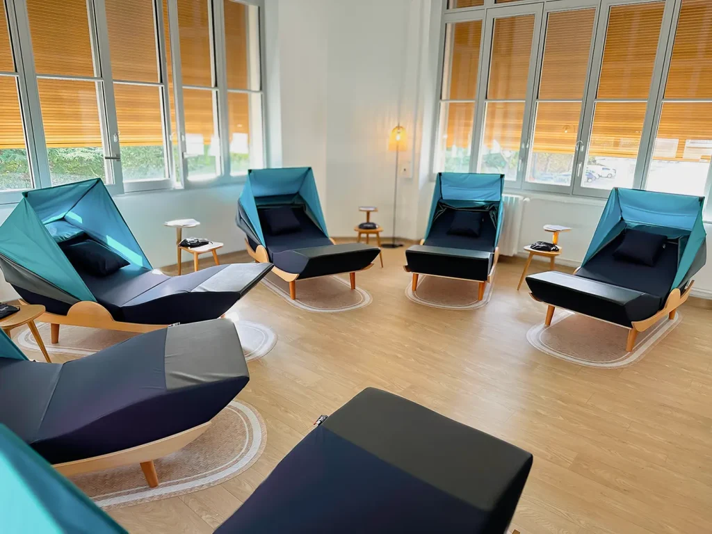 Vue d'ensemble d'une salle de repos avec six fauteuils de sieste bleu marine face à de grandes fenêtres