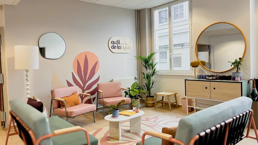 Espace repos chaleureux avec fauteuils et canapés moderne rose et vert, mur décoré et lumière naturelle